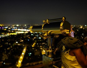 Woman with her phone on the Eiffel Tower at night