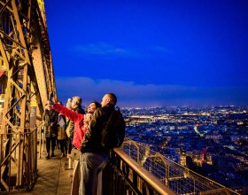 A couple taking a selfie with a glass of champagne on the 2nd floor of the Eiffel Tower