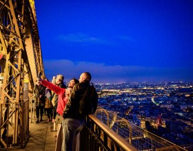 A couple taking a selfie with a glass of champagne on the 2nd floor of the Eiffel Tower