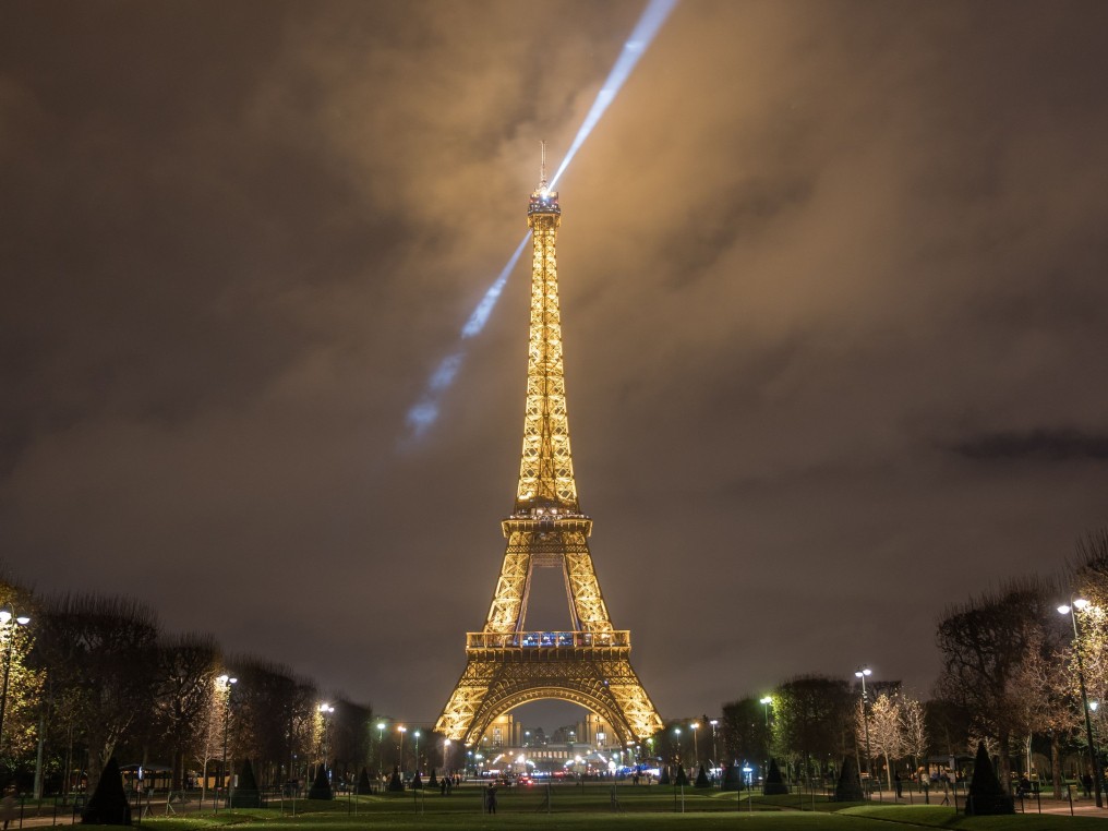 The illuminated Eiffel Tower seen from the Champ de Mars